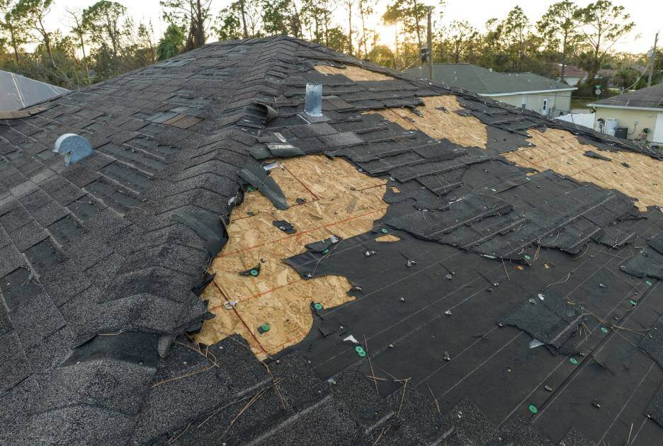 Damaged roof. Wood underneath tiles exposed.